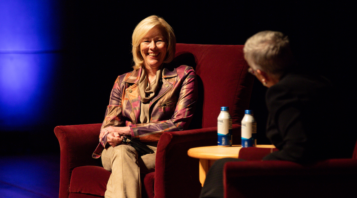 Michelle Livingstone sitting in an armchair interviewing someone on stage.