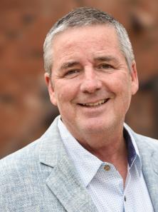A smiling gray-haired man in a nice blazer.