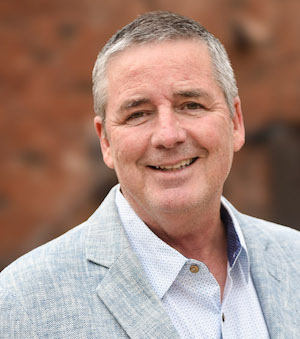 A smiling man in a gray jacket
